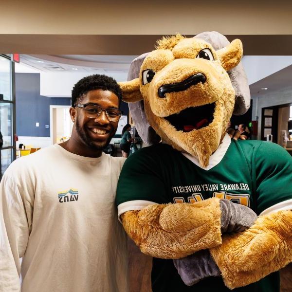 Caesar the mascot with a smiling student in the dining hall. 